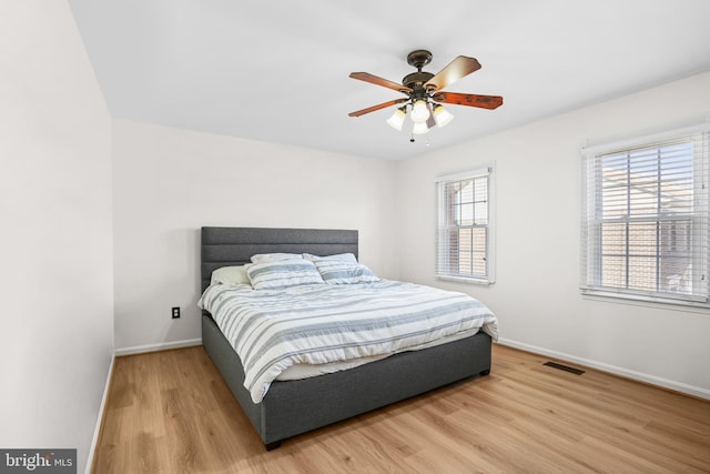 bedroom featuring baseboards, light wood-style flooring, and visible vents