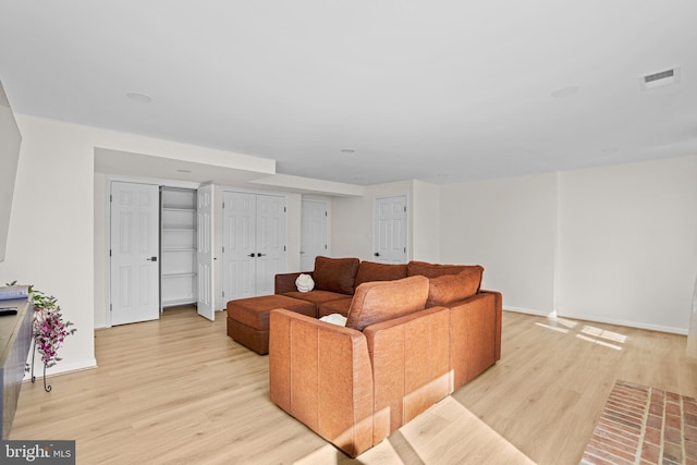 living room with light wood finished floors, baseboards, and visible vents