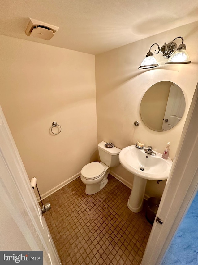 bathroom with toilet, baseboards, and tile patterned flooring