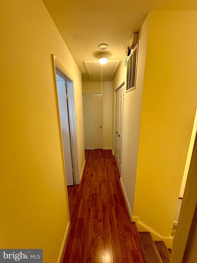 hall with attic access, wood finished floors, and baseboards