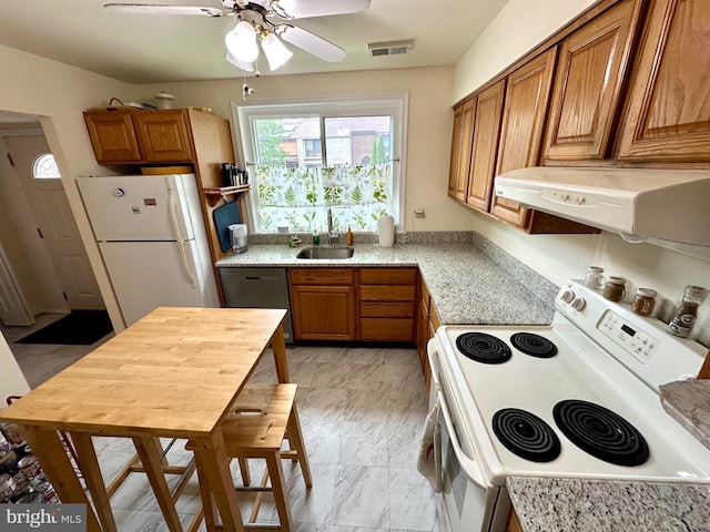 kitchen with white appliances, a sink, under cabinet range hood, and brown cabinets