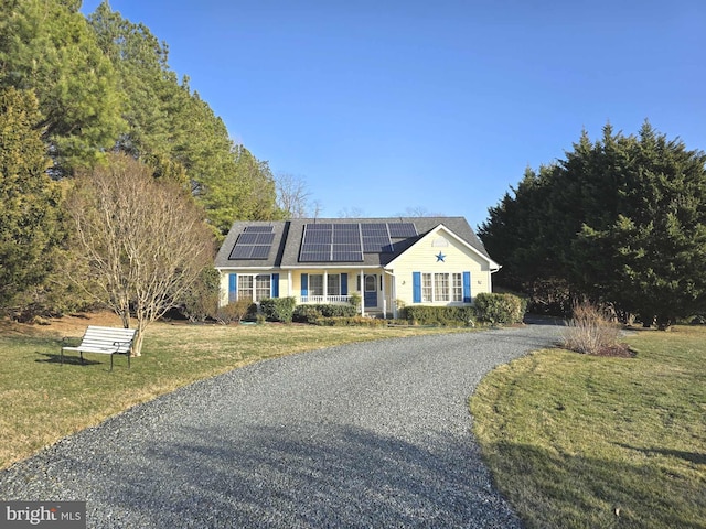 view of front of property with covered porch, a front yard, driveway, and solar panels
