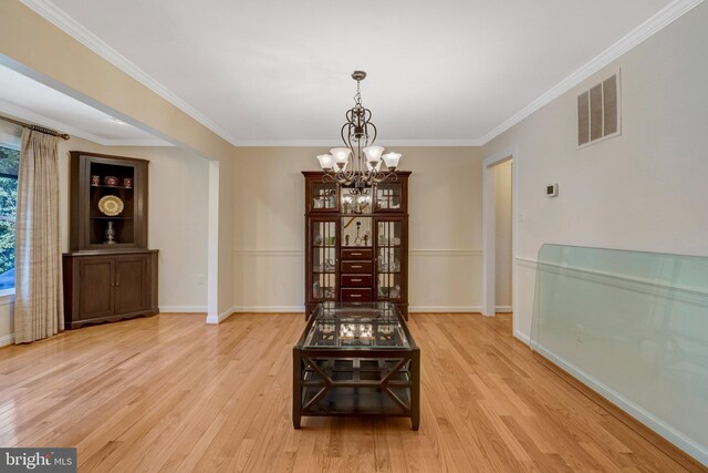 dining area featuring light wood finished floors, visible vents, a chandelier, and crown molding