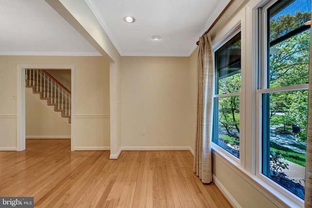empty room featuring baseboards, stairs, light wood finished floors, and a wealth of natural light