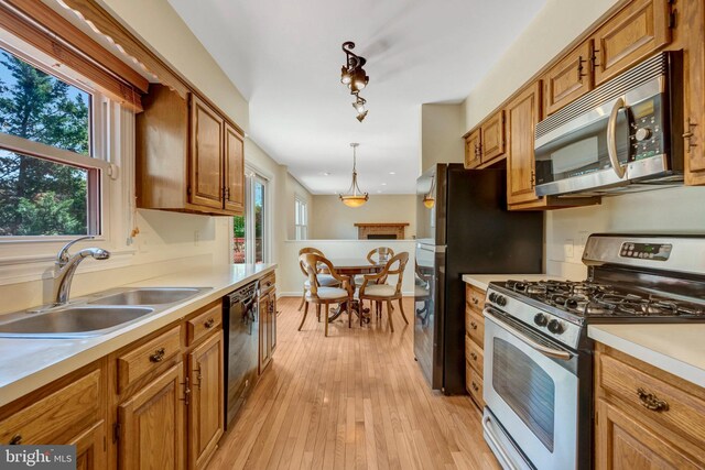 kitchen with brown cabinets, stainless steel appliances, light countertops, and a sink
