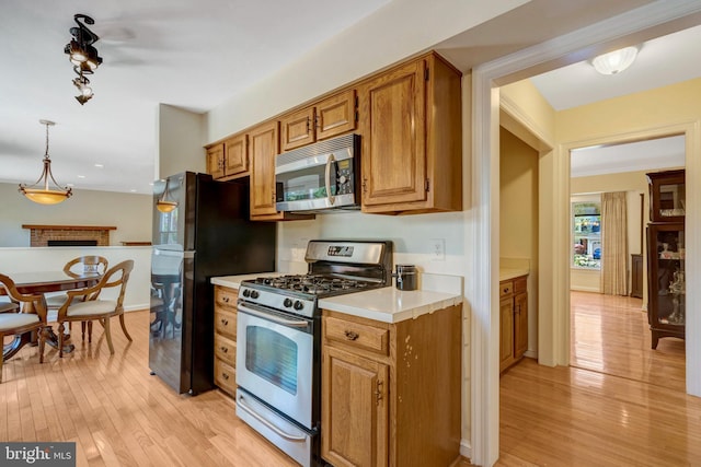 kitchen with light wood finished floors, stainless steel appliances, light countertops, and brown cabinets