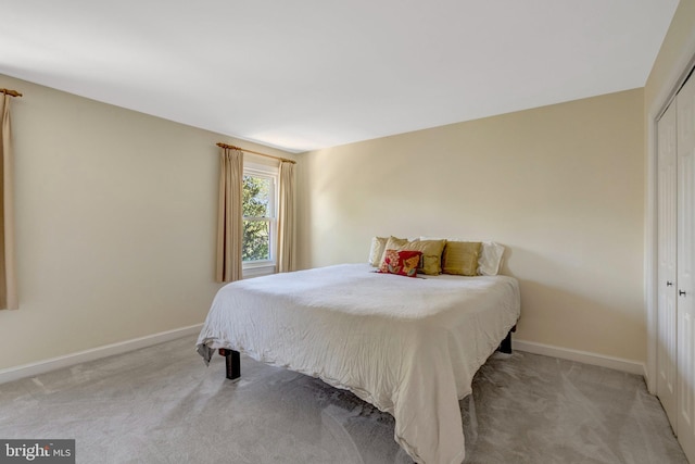 bedroom featuring a closet, baseboards, and light colored carpet