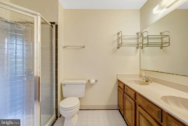 full bath featuring a sink, a shower stall, double vanity, and toilet