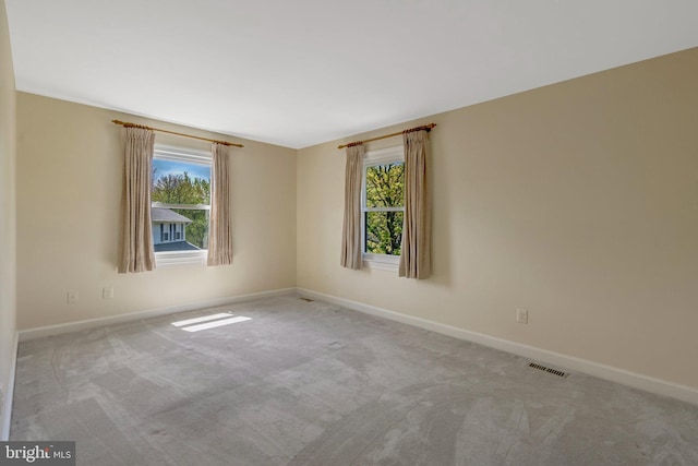 carpeted spare room with visible vents and baseboards