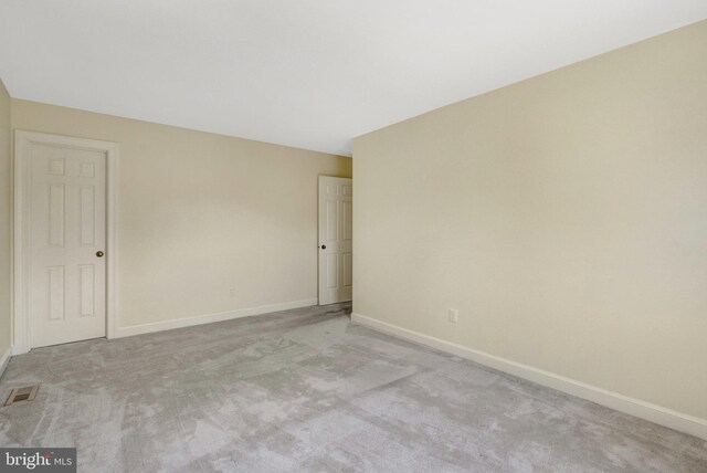 carpeted spare room with visible vents and baseboards