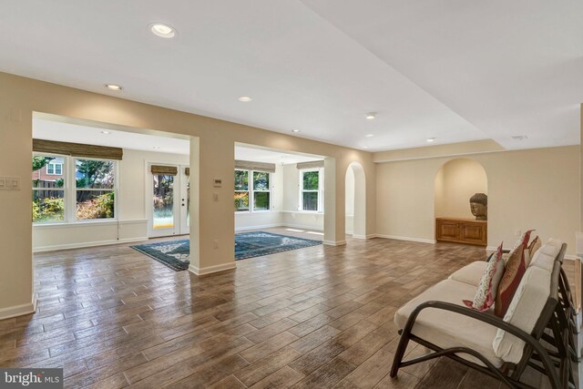interior space with arched walkways, wood finished floors, a wealth of natural light, and baseboards