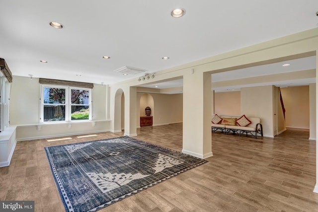 unfurnished living room with recessed lighting, arched walkways, and light wood-style flooring