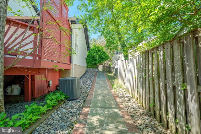 view of property exterior with fence, a wooden deck, and cooling unit