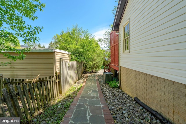 view of side of home with central air condition unit and fence