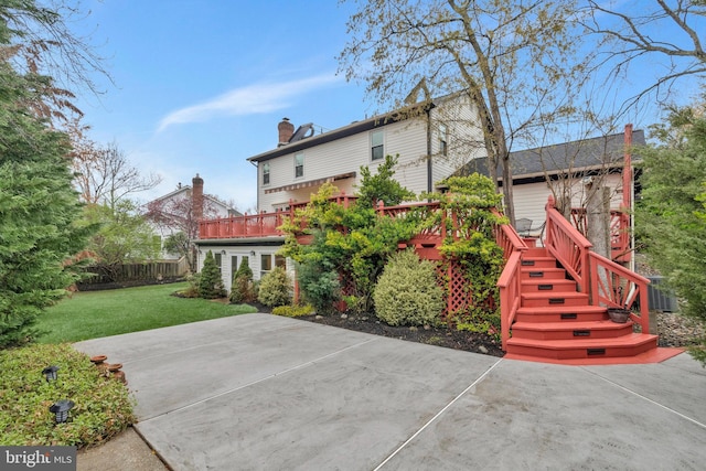 rear view of house with central AC, a chimney, a deck, a yard, and a patio