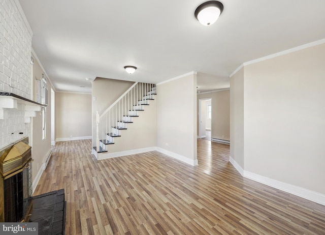 909 Spruce Ave, Pleasantville, NJ 08232 - unfurnished living room with a baseboard heating unit, stairs, baseboards, light wood-style floors, and a brick fireplace