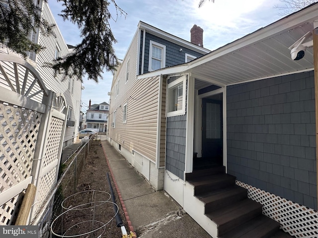 view of property exterior with a chimney, fence, and entry steps
