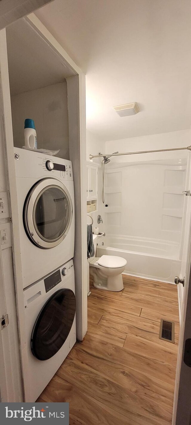 2920 Dares Beach Rd, Prince Frederick, MD 20678 - bathroom with stacked washer / drying machine, shower / tub combination, wood finished floors, and toilet