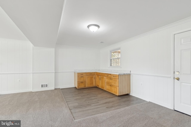 interior space with a decorative wall, visible vents, carpet flooring, and ornamental molding