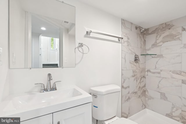 full bath with toilet, vanity, and a tile shower