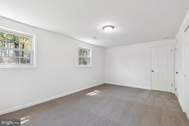 unfurnished room with a wealth of natural light, carpet flooring, and baseboards