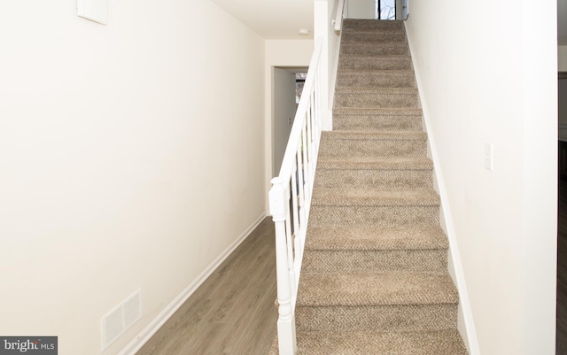 stairs with baseboards, visible vents, and wood finished floors