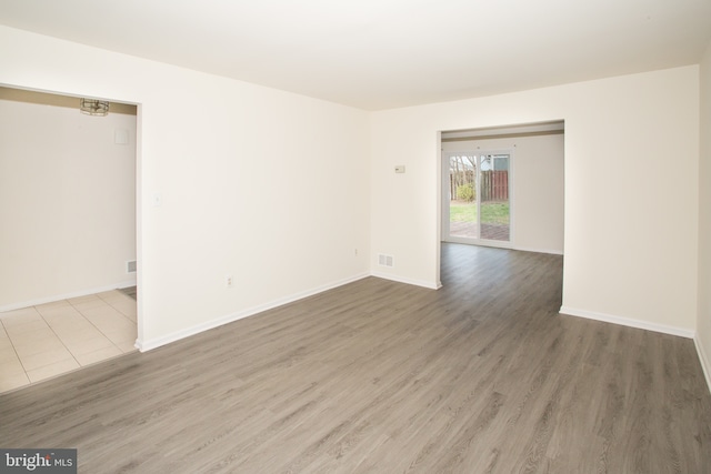 empty room featuring visible vents, baseboards, and wood finished floors