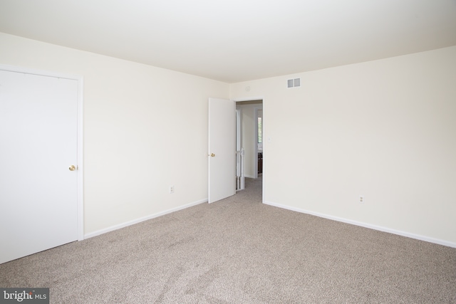 carpeted empty room featuring baseboards and visible vents