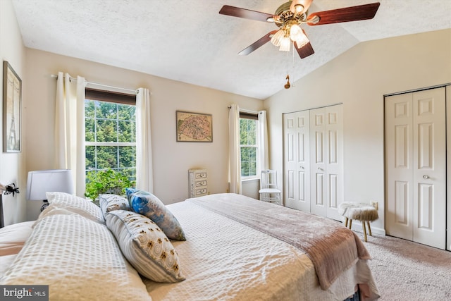 bedroom with carpet, two closets, ceiling fan, and vaulted ceiling
