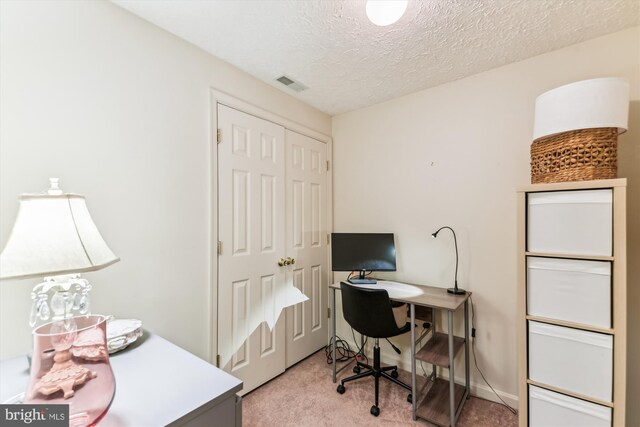 office area featuring a textured ceiling, visible vents, and light colored carpet