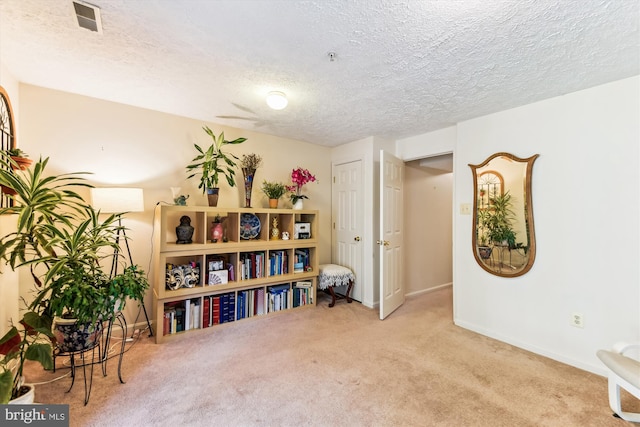 living area featuring baseboards, visible vents, a textured ceiling, and carpet floors