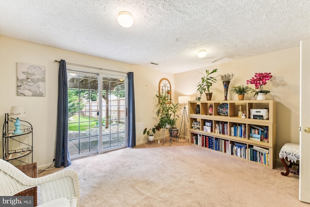 living area with a textured ceiling, visible vents, carpet flooring, and baseboards