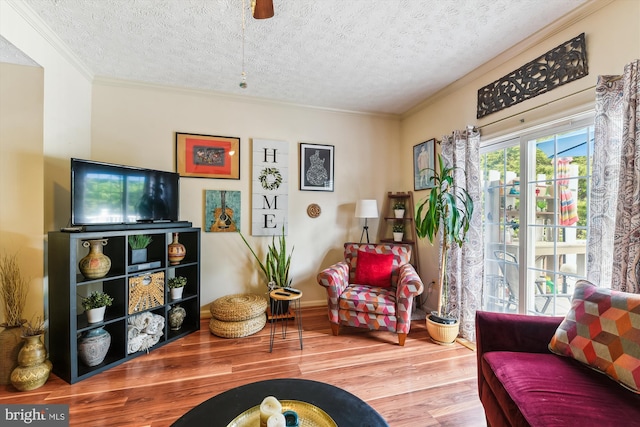 sitting room with a textured ceiling, wood finished floors, a ceiling fan, and ornamental molding