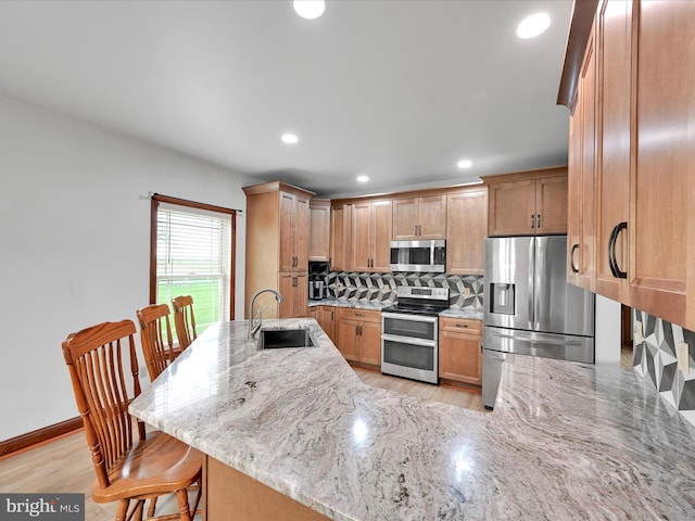 kitchen featuring tasteful backsplash, recessed lighting, light stone counters, a sink, and stainless steel appliances