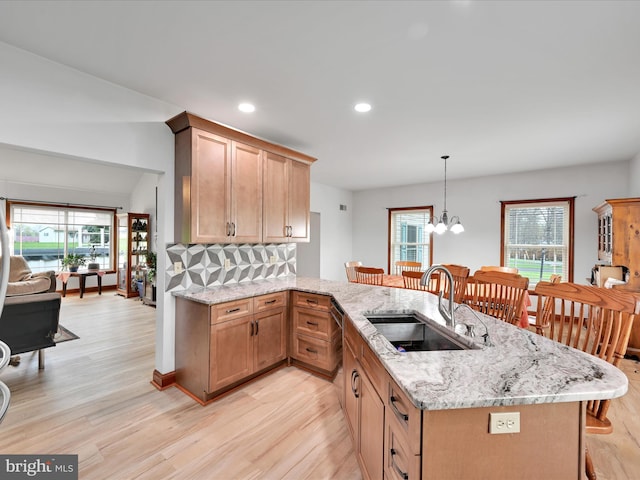 kitchen with a peninsula, a kitchen breakfast bar, light wood-type flooring, and a sink