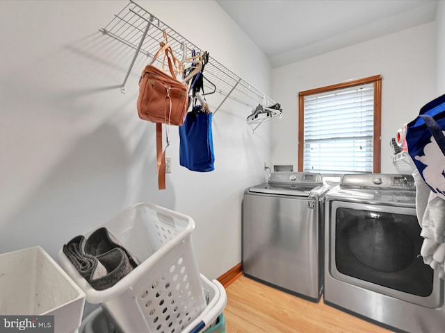 clothes washing area featuring light wood-type flooring, washing machine and dryer, laundry area, and baseboards