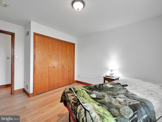 bedroom featuring light wood-type flooring, a closet, baseboards, and visible vents