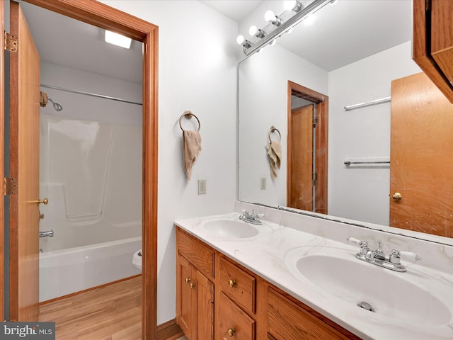 full bathroom with a sink, double vanity, wood finished floors, and tub / shower combination