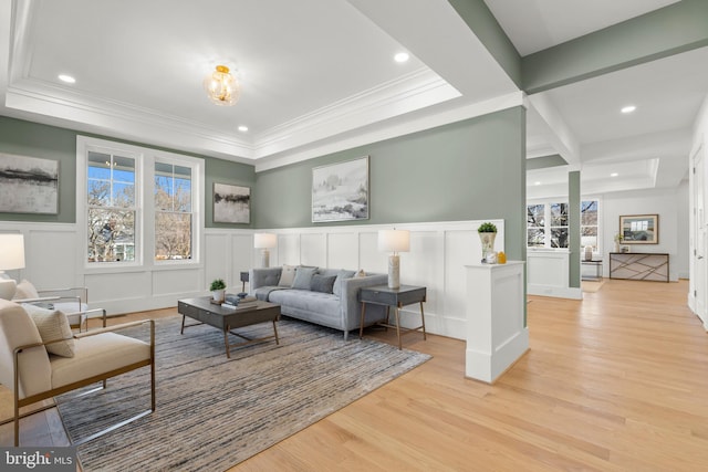 living area with a decorative wall, recessed lighting, light wood-style floors, and a raised ceiling