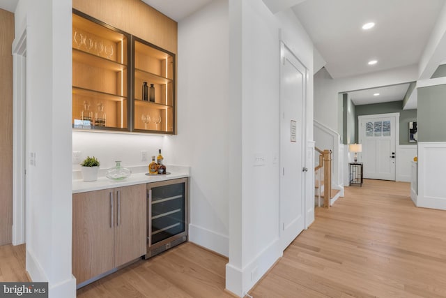 bar featuring a bar, light wood-style flooring, recessed lighting, and beverage cooler