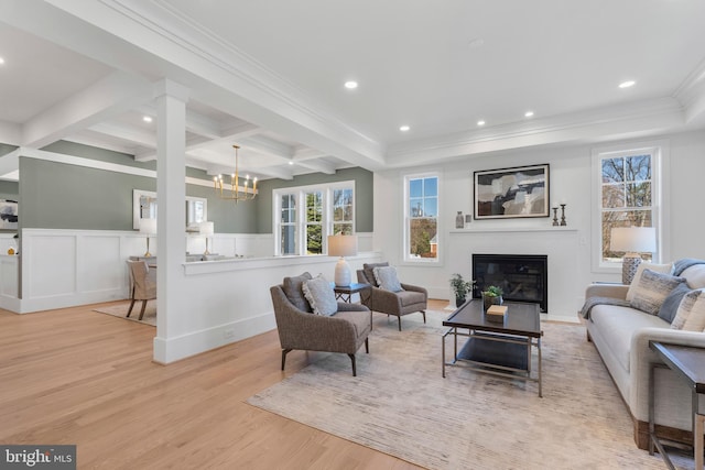 living room with coffered ceiling, a wainscoted wall, beam ceiling, a glass covered fireplace, and wood finished floors