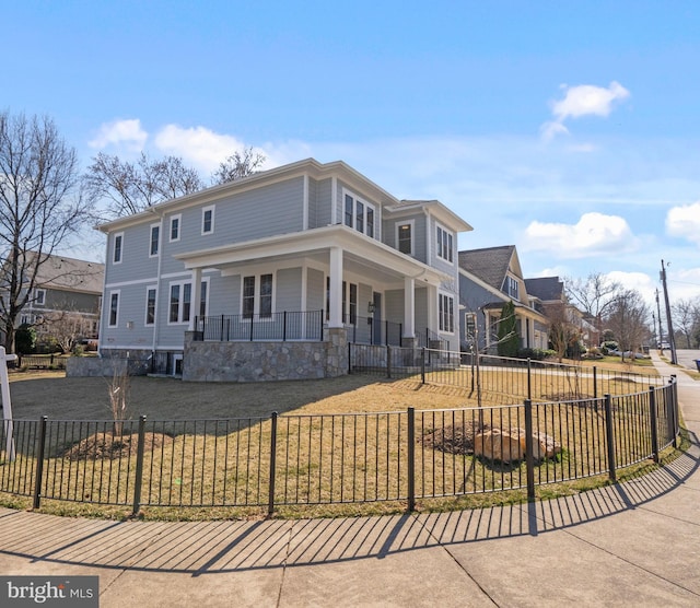 view of front of house featuring a front lawn, a fenced front yard, covered porch, and stone siding