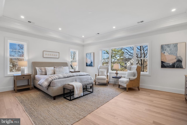 bedroom featuring a tray ceiling, visible vents, light wood-type flooring, and ornamental molding