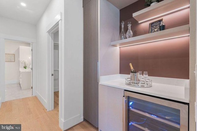 bar with baseboards, a dry bar, light wood-style floors, and beverage cooler