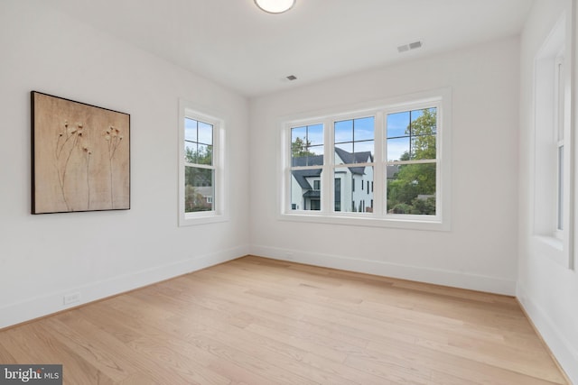 spare room featuring baseboards, visible vents, and light wood-style flooring
