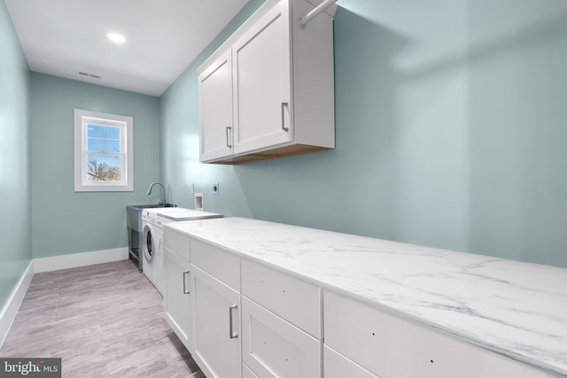washroom with visible vents, light wood-style flooring, baseboards, cabinet space, and washer / dryer