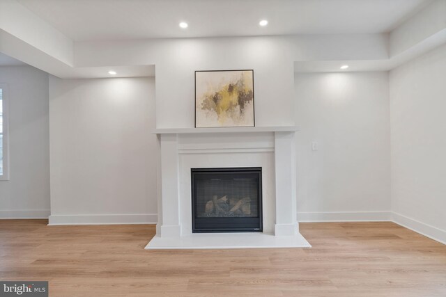 details featuring a glass covered fireplace, baseboards, and wood finished floors