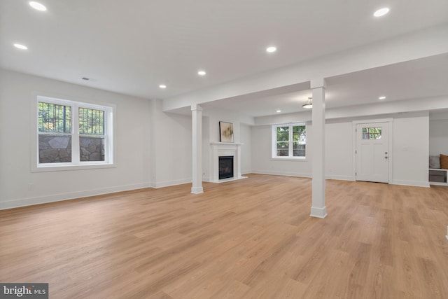 unfurnished living room featuring baseboards, a fireplace, recessed lighting, and light wood finished floors