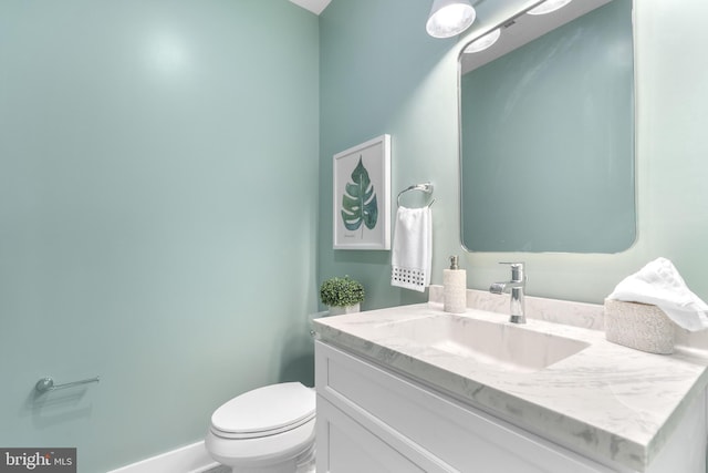 bathroom with toilet, vanity, and baseboards