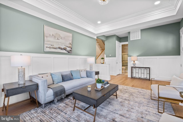 living area with a tray ceiling, wood finished floors, visible vents, ornamental molding, and recessed lighting